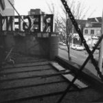 Black and white photo of a rooftop. There is a sign, but the words are backwards. If they were forwards, they would read Regent