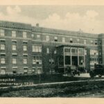 Sepia photo of a large, four storey brick building.