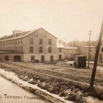Sepia toned image of a large brick building beside a creek. There are words reading Robson's Tannery Cedardale