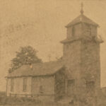 Sepia toned image of a church with a cross on top of a pyramid shaped spire