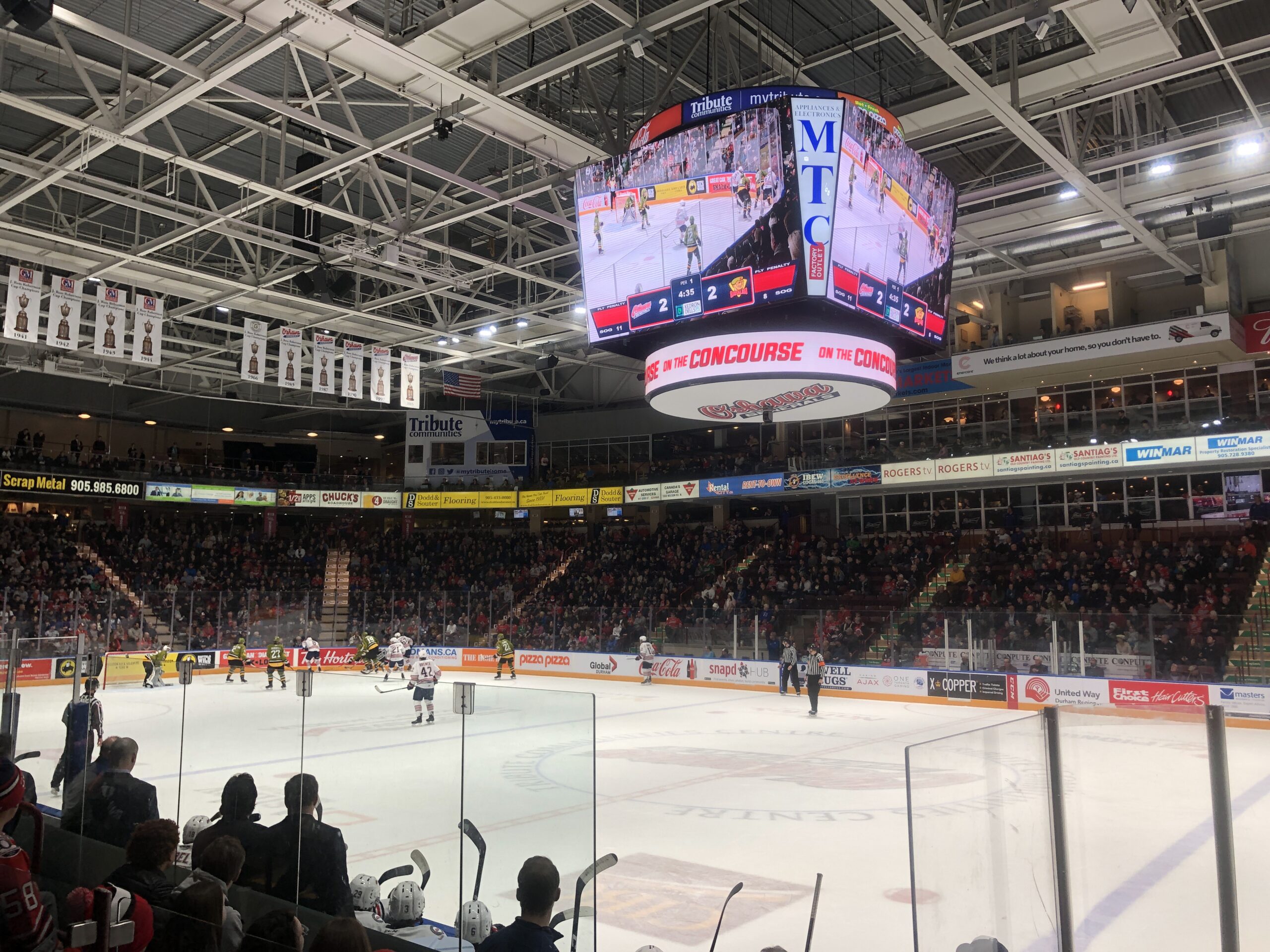 The Oshawa Generals face off against North Bay Battalion, players are fighting for the puck on the opposite end of the rink to where the photo was taken. The score is 2-2.