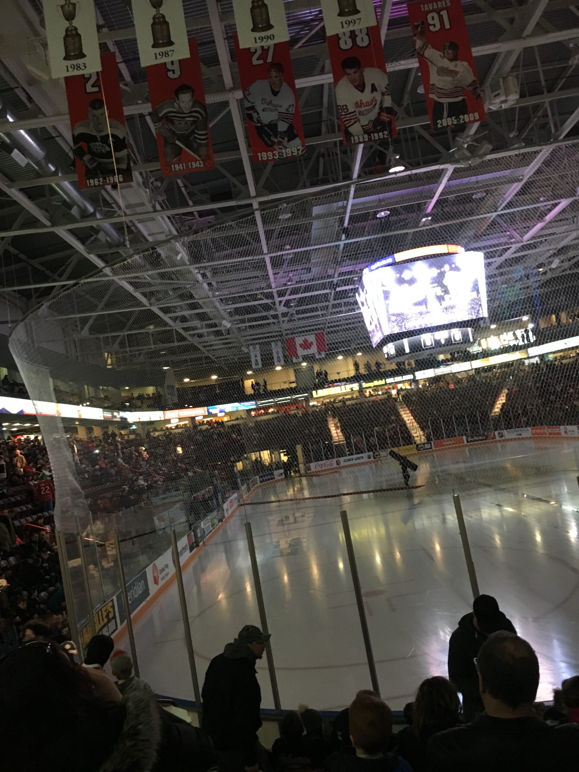 An empty rink, semi darkened, just before the Oshawa Generals play. Photo taken from one end of the rink, a couple rows up from ground level