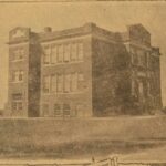 Sepia photograph of a two storey brick building with large windows