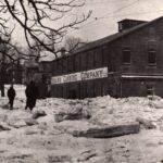 Black and white photograph of a building with a sign reading Oshawa Canning Company. It is winter as there is a lot of snow on the ground
