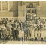 Sepia photo of a group of children in front of a brick school
