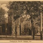 Sepia image of a church, partially obscured by large trees.