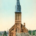 Colourized image of a church with a very large centre spire