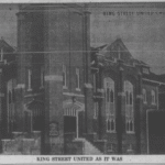 Black and white newspaper photograph of a large brick building.