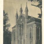 Sepia toned image of a brick church. There are two people standing out front.