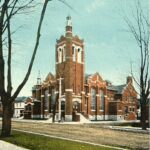 Colourized postcard of a large, brown brick building.