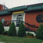 Colour photo of a red brick building with a green metal roof. The sign above the door reads "New Globe Restaurant"