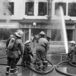 Black and white photo of six fire fighters working to put out a fire